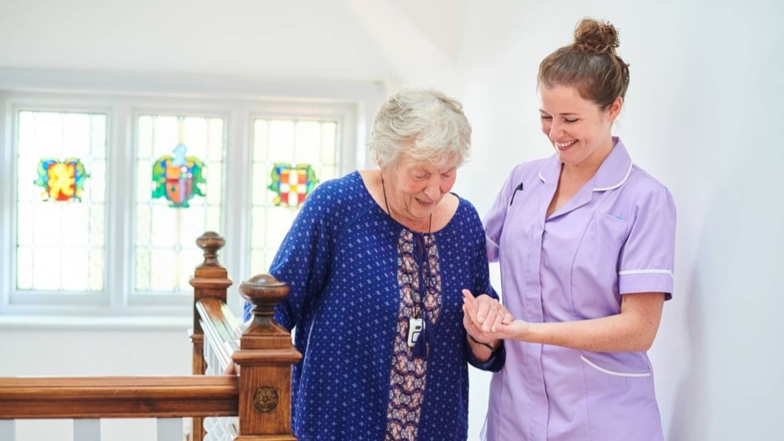 dementia care assistant helping an elderly lady down her stairs at home