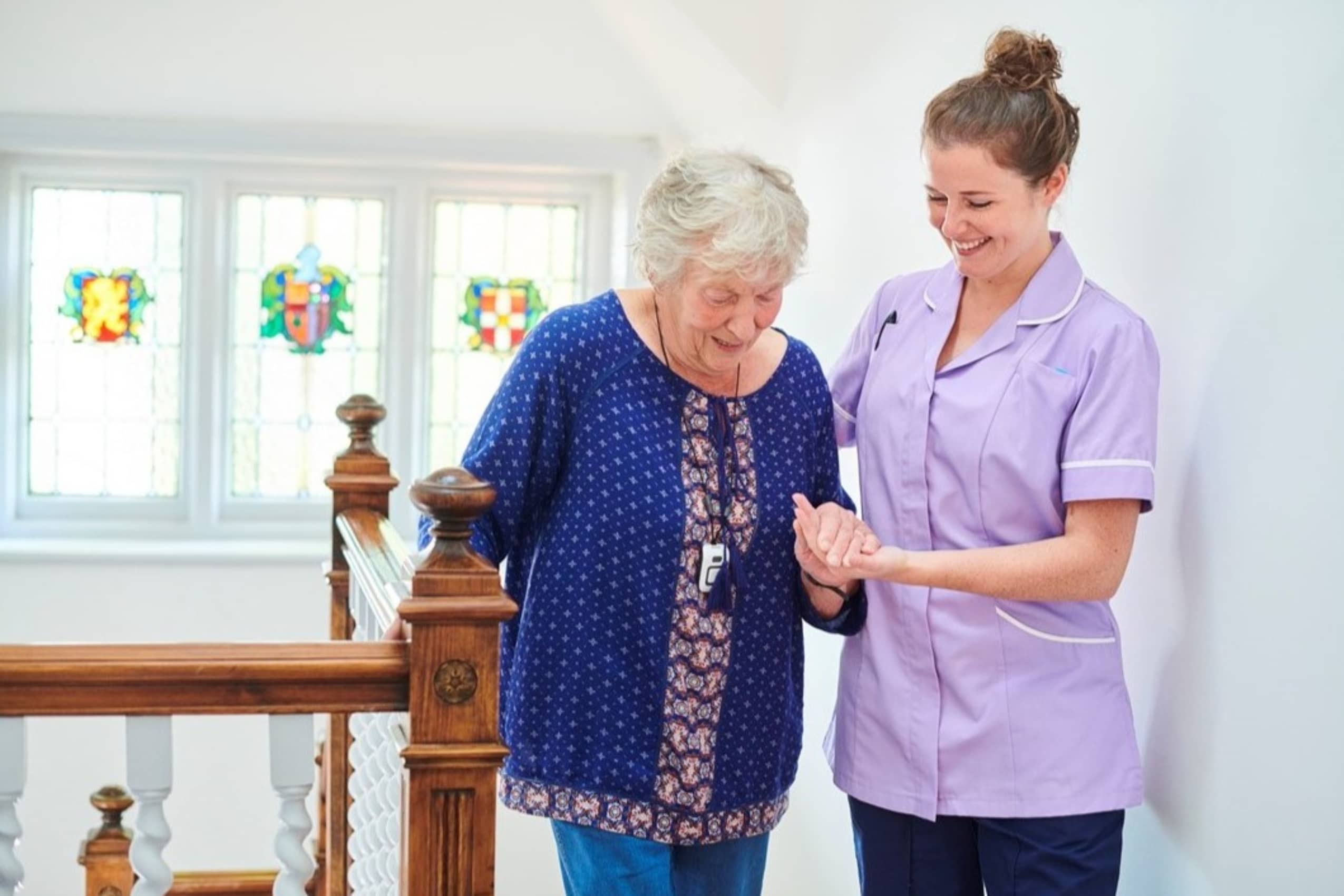 a women working in respite care helping an elderly lady up the stairs