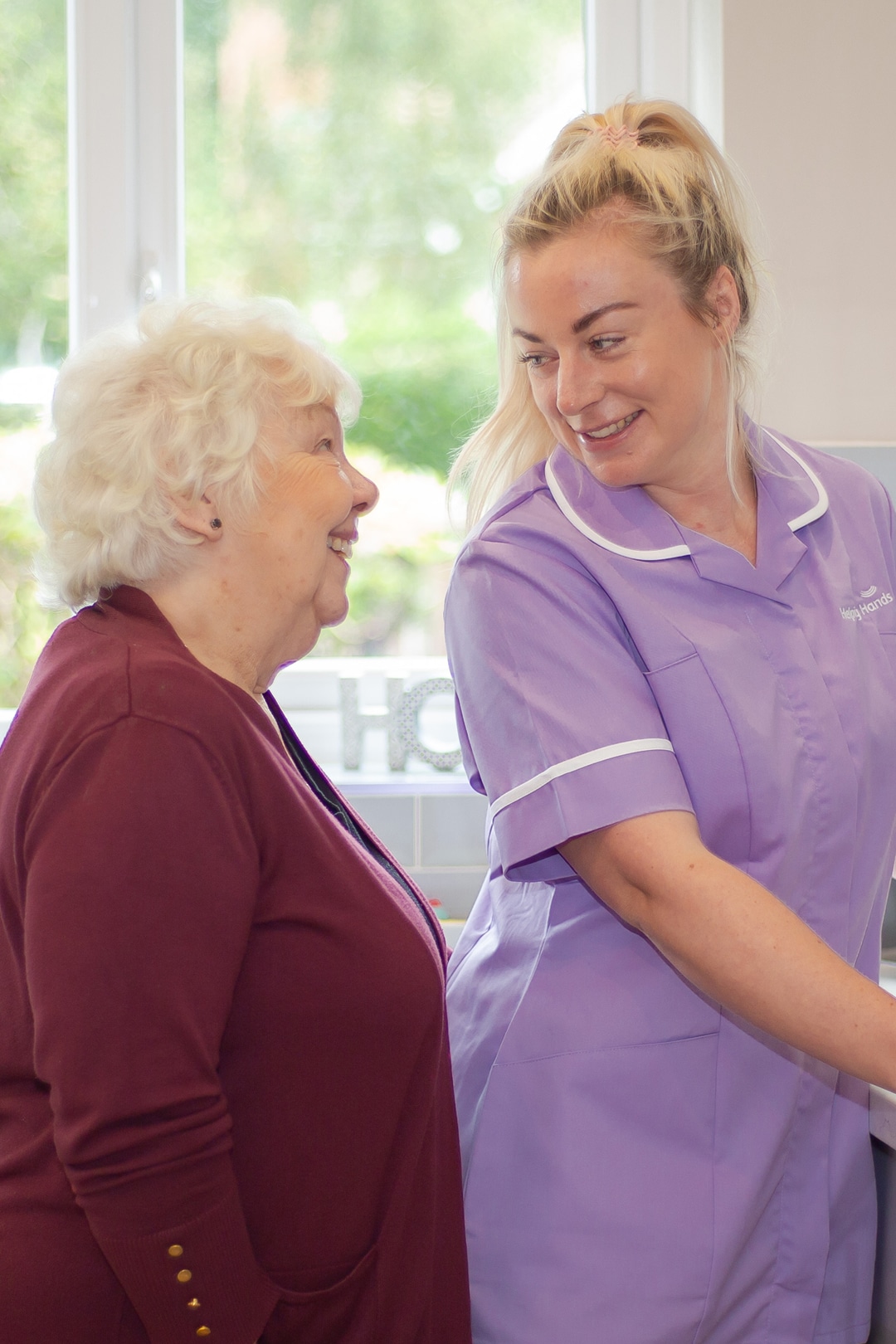 personal carer smiling at an elderly customer in the kitchen
