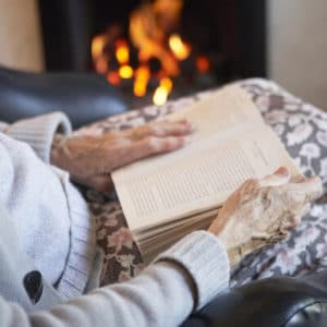 An elderly lady at home next to the fire